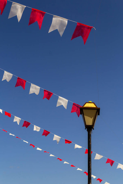 Een straatlamp vintage, met een lijn van witte en rode vlaggen, met blauwe lucht op de achtergrond. Lampenpost. Lamp met vlaggen. - Foto, afbeelding