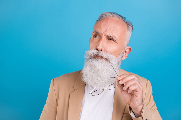Portrait of handsome bewildered grey-haired man overthinking copy space isolated over bright blue color background. - Foto, imagen