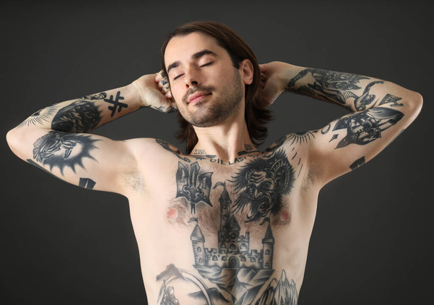 Young man with tattoos on body against black background - Photo, image