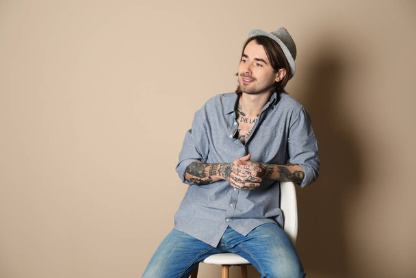 Young man with tattoos on body against beige background - Zdjęcie, obraz
