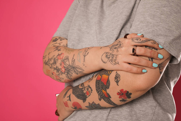 Woman with tattoos on arms against pink background, closeup - Fotografie, Obrázek