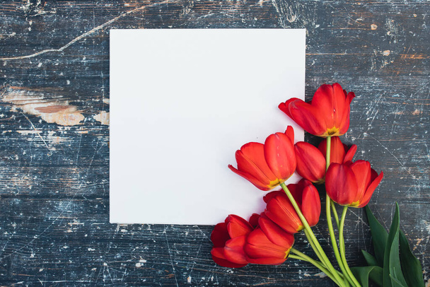 Fresh tulips bouquet and blank card for copy space over wooden table background - Fotó, kép