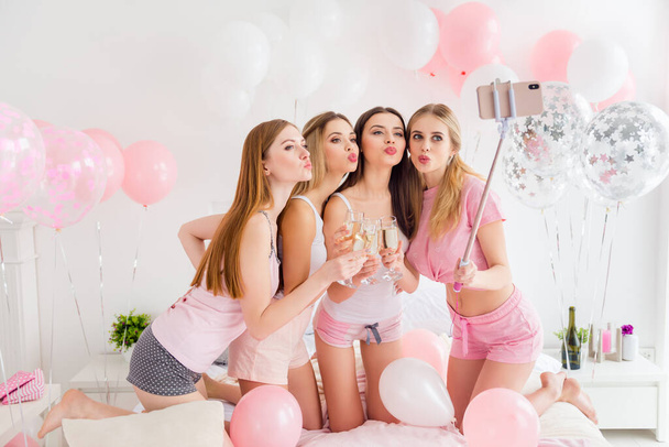 Portrait of four gorgeous charming girls hold selfie stick make photo kiss lips drink champagne indoors. - Foto, Imagem