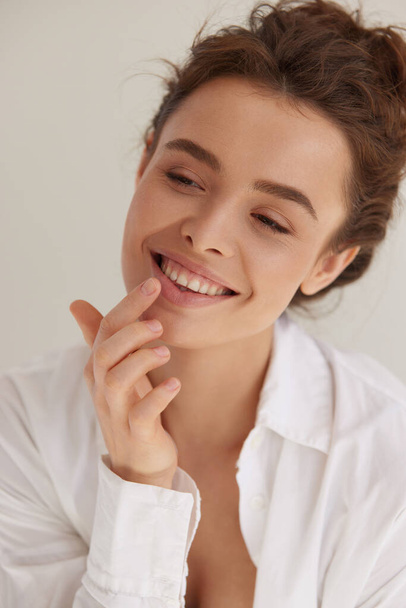 Lips care. Positive young woman with wavy brown hair using cosmetic balm for moisturizing her sexy plump lips. Skin care and beauty concept. - Φωτογραφία, εικόνα