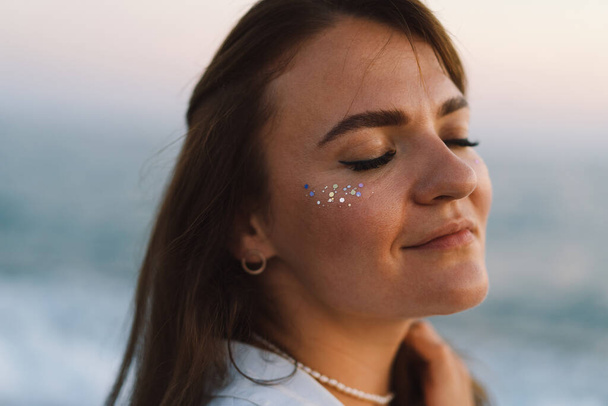 Portrait of a happy young girl with closed eyes on a background of beautiful sea. The girl looks at the magical sea. Freedom and happiness - Foto, Imagen