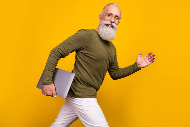 Portrait of attractive trendy grey-haired man going carrying laptop meeting isolated over bright yellow color background. - Foto, immagini