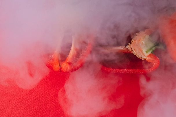 DOCE, fresco vermelho PEPPER em um vermelho BACKGROUND, cortar ao meio, fumaça grossa ao redor. nutrição adequada. produtos hortícolas frescos - Foto, Imagem