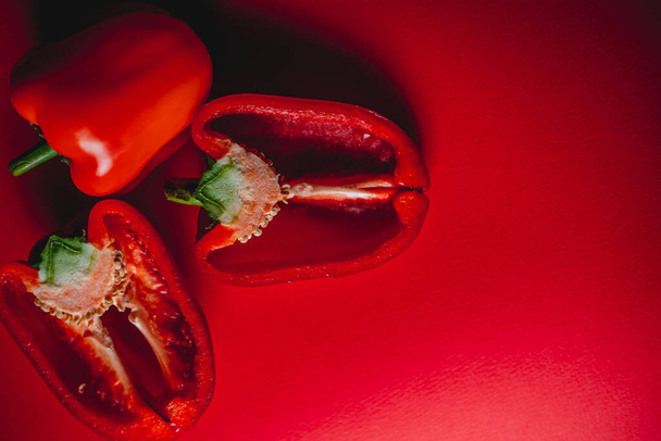 SWEet, friss, piros PEPPER egy piros háttámlán, félbevágva. fotó az étlapra, megfelelő táplálkozás. friss zöldségek. - Fotó, kép