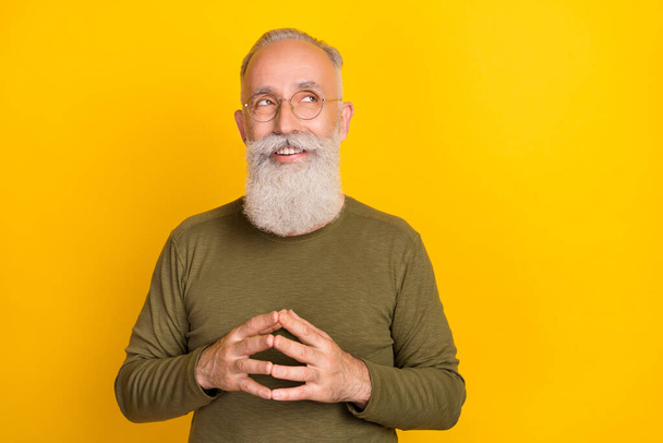 Photo of positive smart sly grandpa hold fingers look empty space wear green shirt isolated yellow color background. - 写真・画像