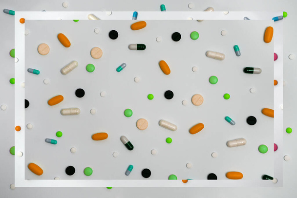 Разнообразие лекарств в капсулах и таблетках разных цветов на белом фоне - Фото, изображение