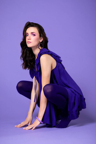 Portrait of lovely girl with violet purple outfit, isolated over violet purple background. Purple violet make-up. - Foto, imagen