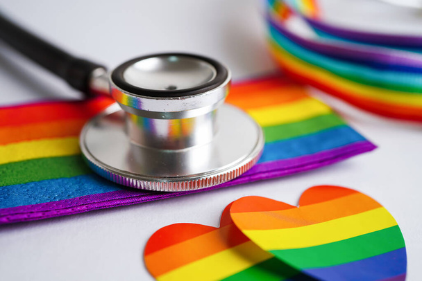 Black stethoscope on rainbow flag background, symbol of LGBT pride month celebrate annual in June social, symbol of gay, lesbian, bisexual, transgender, human rights and peace.  - Photo, Image