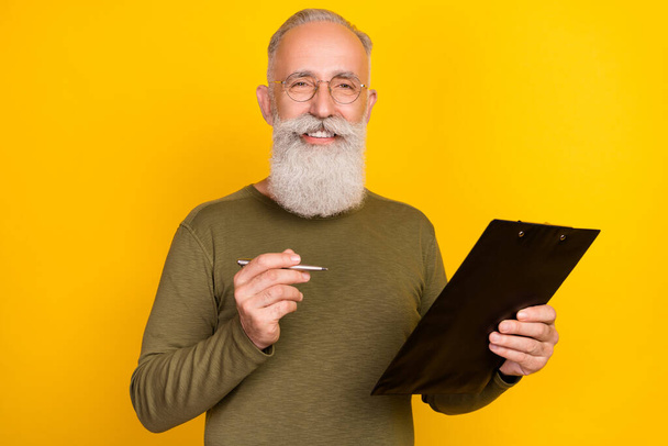 Photo of joyful old white beard man write wear eyewear green sweater isolated on yellow color background. - Foto, afbeelding