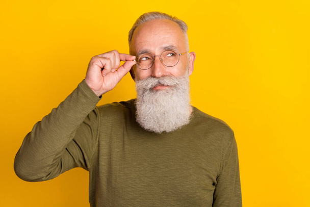 Photo of clever aged grey beard man touch eyewear look empty space wear green sweater isolated on yellow color background. - Foto, Imagem