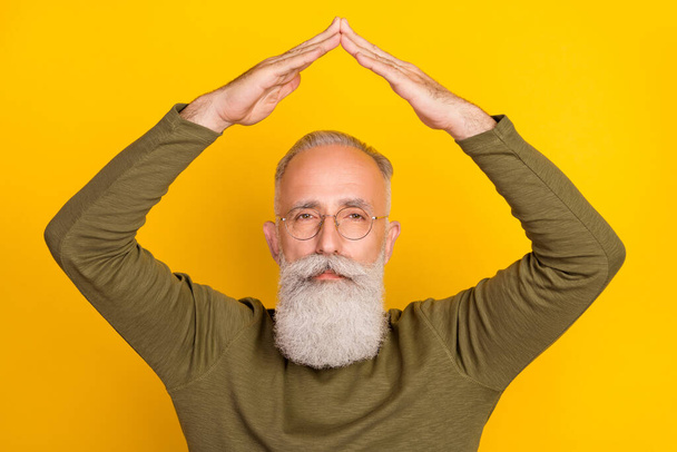 Photo of strict aged grey beard man hands up wear eyewear green sweater isolated on yellow color background. - Foto, Imagem