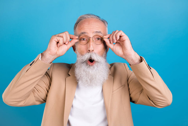 Portrait of handsome amazed classy grey-haired man expert touching specs wow reaction isolated over bright blue color background. - Foto, immagini