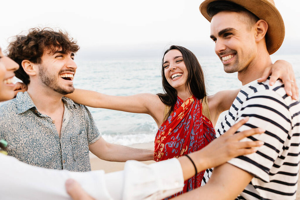 Egy csapat boldog fiatal barát, akik együtt nevetnek, miközben szórakoznak a nyári vakációkon a strandon. - Fotó, kép