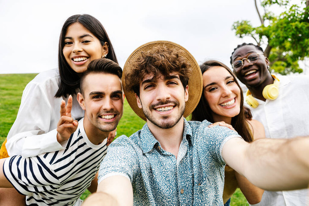 Young group of multiracial friends taking selfie together outdoors - Millennial people having fun enjoying summer vacation - Multicultural friendship and holidays concept - Foto, Bild