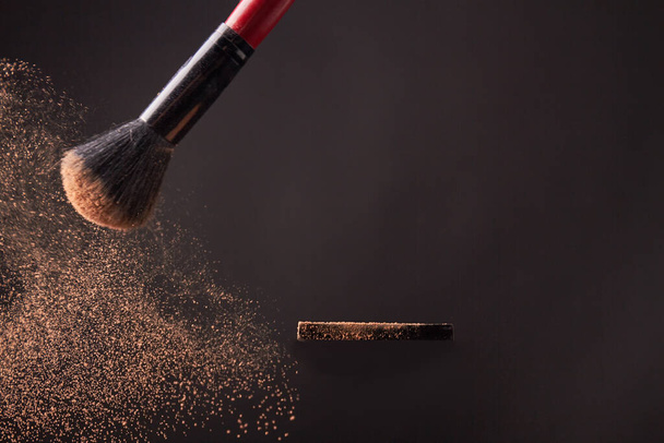Makeup brush with beige color powder splashes. Isolated on gray background. - Photo, Image