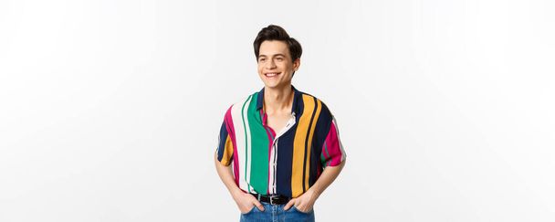 Image de beau jeune homme en chemise d'été colorée regardant heureux, debout sur fond blanc. - Photo, image