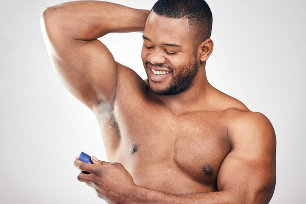 Estudio de un joven guapo rociando desodorante en su axila sobre un fondo blanco - Foto, Imagen