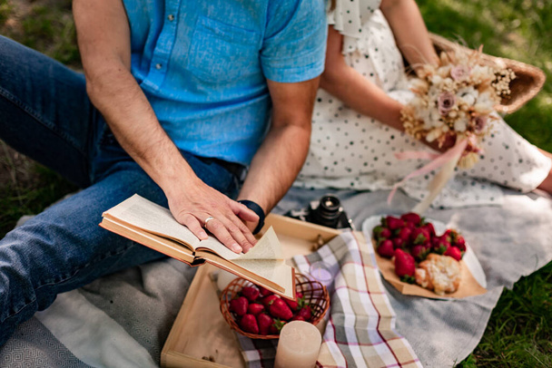 man holding a book at a picnic.Close up, outdoors. Picnic in nature concept. High quality photo - Photo, Image