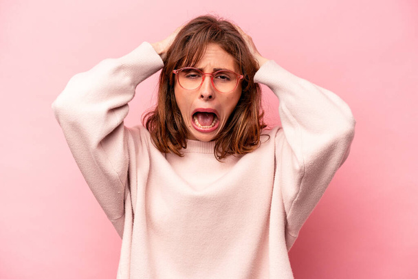 Young caucasian woman isolated on pink background screaming, very excited, passionate, satisfied with something. - Fotoğraf, Görsel