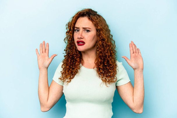 Young ginger caucasian woman isolated on blue background being shocked due to an imminent danger - Photo, Image