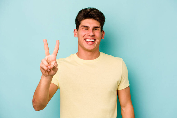 Fiatal fehér férfi elszigetelt kék háttér mutatja a második számú ujjak. - Fotó, kép