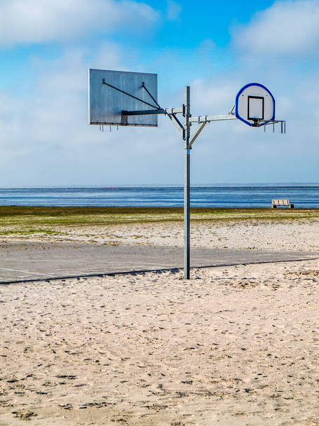 Halbseitige Ansicht eines beidseitigen Street-Basketballkorb-Mastes am Nordseestrand in Harlesiel Ostfriesland vor blauem Himmel in vertikaler Ausrichtung. - Foto, Bild