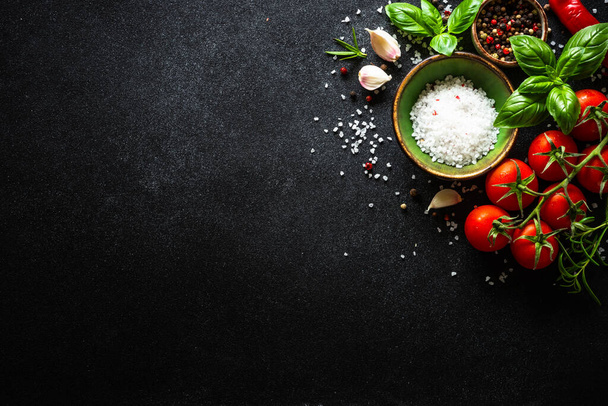 Élelmiszer háttér fekete kő asztal zöldségek, gyógynövények és fűszerek. Felülnézet másolási hellyel. - Fotó, kép