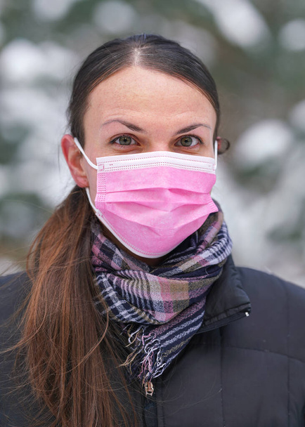 Young woman in winter jacket with pink disposable single use face virus mask - Фото, зображення