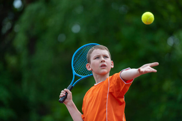 Gyermek teniszütővel a teniszpályán. Képzés fiatal gyerekeknek, egészséges gyerekek. Horizontális sport téma plakát, üdvözlőlapok, fejlécek, weboldal és alkalmazás - Fotó, kép