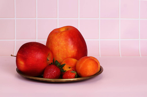Bio raw fresh apricots strawberry, fruits on plate in kitchen, copy space - Фото, изображение