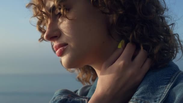 Closeup upset woman posing at seaside. Thoughtful girl touching neck with hand. Postrait girl face with curly hair. Pretty lady looking ocean horizon. Attractive woman feeling lonely. Sadness concept - Footage, Video