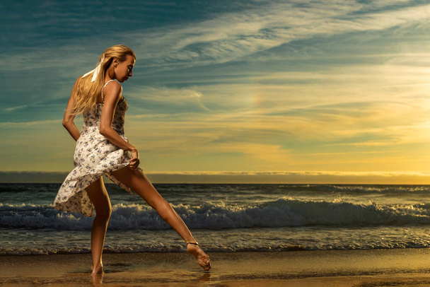 Beautiful party girl dancing on the beach over sunset background - Photo, image