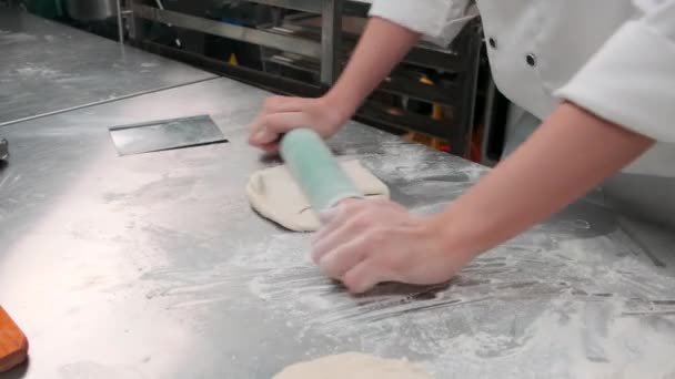 Close-up van de hand chef-kok in witte kok uniformen met schorten zijn het kneden van deeg deeg met roller, het bereiden van brood, taarten, en vers bakkerij voedsel, bakken in de oven in roestvrij stalen keuken van restaurant. - Video