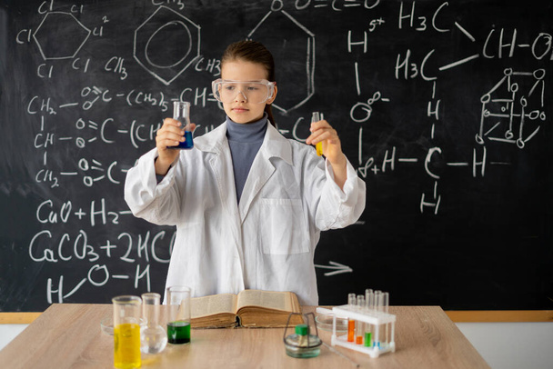 школярка проводить хімічний експеримент. маленький студент на уроці хімії в лабораторії. наукові експерименти в класовій діяльності. Концепція освіти
 - Фото, зображення