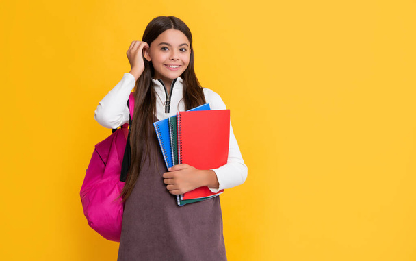 happy child with school backpack and notebook on yellow background. - Valokuva, kuva