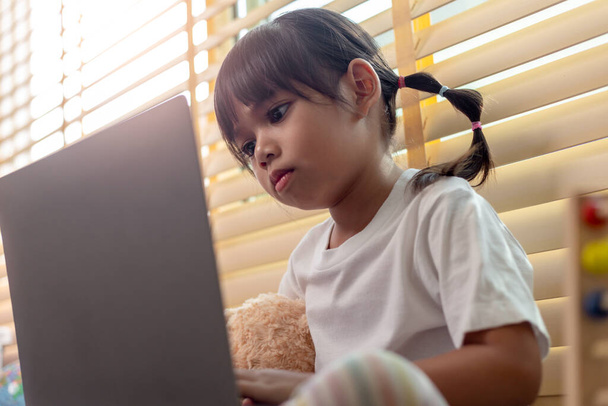 Asiatique fille à l'aide d'un ordinateur portable pour l'étude en ligne à domicile pendant la quarantaine à domicile. l'enseignement à domicile, l'étude en ligne, la quarantaine à domicile, l'apprentissage en ligne, le virus corona ou le concept de technologie éducative - Photo, image