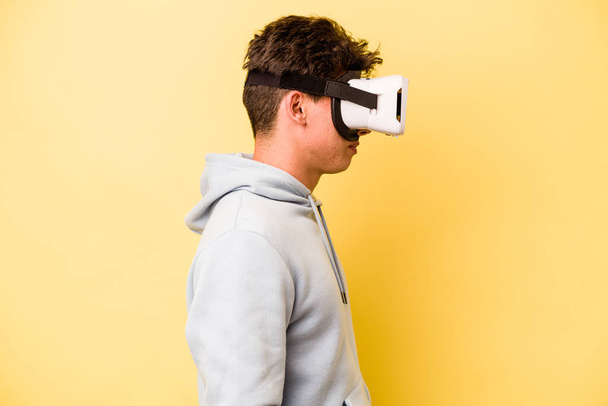 Young caucasian man wearing virtual glasses isolated on yellow background - Foto, immagini