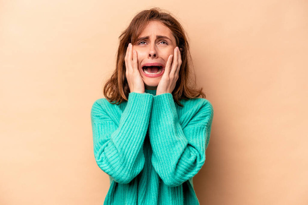 Young caucasian woman isolated on beige background whining and crying disconsolately. - Photo, Image