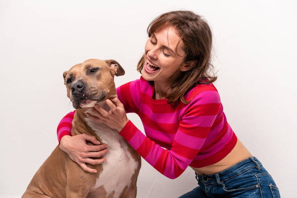 Joven mujer caucásica con su perro aislado sobre fondo blanco - Foto, imagen