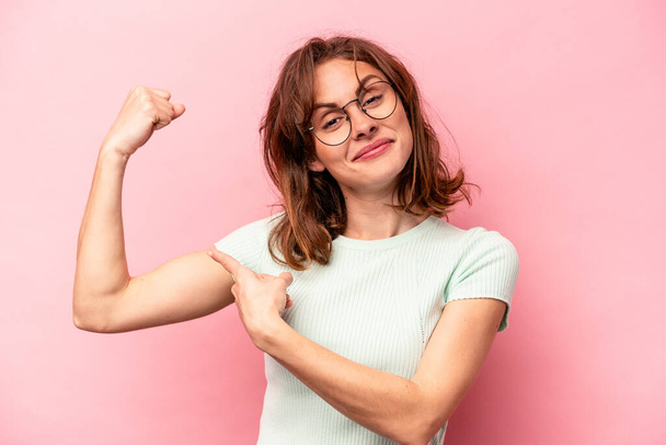 Young caucasian woman isolated on pink background showing strength gesture with arms, symbol of feminine power - Foto, Bild