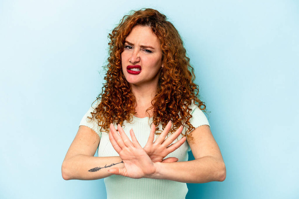 Young ginger caucasian woman isolated on blue background doing a denial gesture - Φωτογραφία, εικόνα