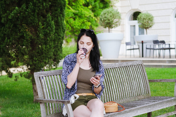 Retrato de una joven mujer de negocios feliz relajándose en la ciudad, café al aire libre. Beber café. Usando el teléfono. Selfie. tecnología. Redes sociales. Videollamada. Vacaciones de verano. Viajes - Foto, imagen