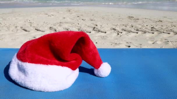 Felvételek a gyönyörű strand Kuba Varadero, mutatja a piros karácsonyi Mikulás kalap kerül az oldalán egy kék napozóágy, Karácsony a nap és a strand koncepció, forgatott 8K minőségű - Felvétel, videó