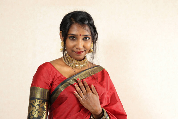 Kırmızı turuncu sari takısı takan Hintli bir kadın. Kolye, jhumka küpe, maang tikka bel zinciri poz. Eski kırsal oda arka planında gülücük ruh haline bakın. - Fotoğraf, Görsel