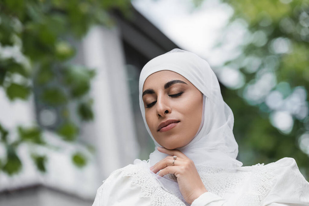 portrait of muslim bride in hijab with diamond ring on finger and closed eyes - Foto, Imagem