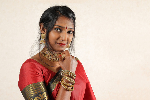 Indická žena na sobě červené oranžové tradiční královské saree šperky choker set náhrdelník jhumka náušnice maang tikka pas řetěz stojan póza vzhled vidět úsměv nálada výraz na staré venkovské místnosti pozadí - Fotografie, Obrázek